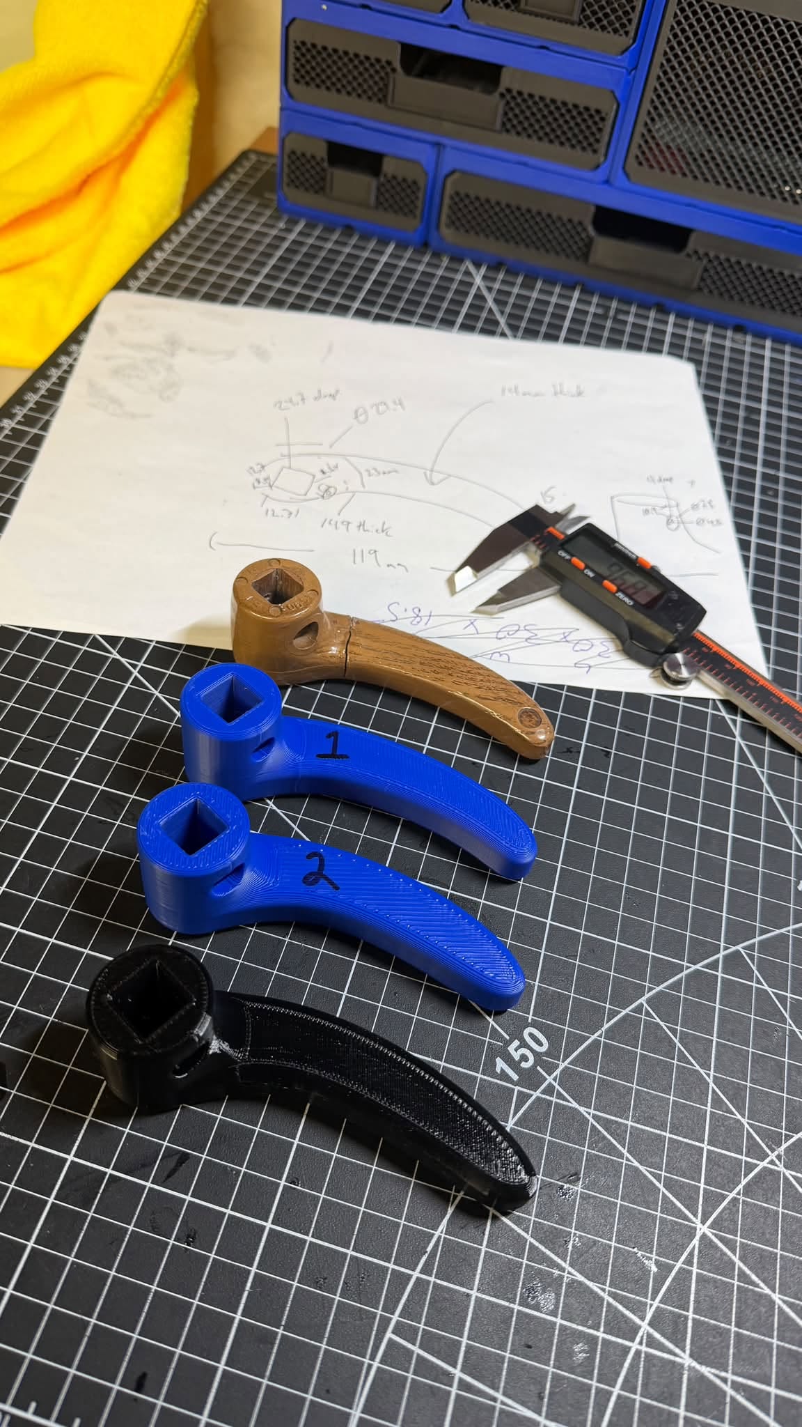 Original recliner handle, two blue prototypes, and the final black printed handle